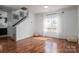 Inviting living room with beautiful hardwood floors, a staircase, and large windows dressed with sheer white curtains at 5032 Meadow Woods Dr, Lowell, NC 28098