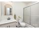 Bright bathroom with a shower, toilet, sink, mirror, and gray wood floors at 604 White Oak Ct, Gastonia, NC 28056