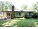 View of the backyard with a patio, brick chimney and natural foliage at 7228 Rollingridge Dr, Charlotte, NC 28211