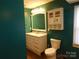 A bathroom with green walls, a white vanity, a mirror, and a standard toilet at 934 W Nc 150 Hwy, Lincolnton, NC 28092