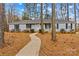 Charming single-story home with light blue siding, black shutters, front porch, and a walkway amidst mature trees at 101 Fairfax Dr, Salisbury, NC 28146