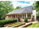 Back exterior view with covered porch, multiple windows and tiered stone landscaping at 1025 Seminole Dr, Waxhaw, NC 28173