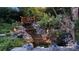 Backyard pond at night with decorative lights, a foot bridge, and lush foliage at 108 Outside Loop Ln, Mooresville, NC 28117