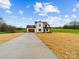 An angle view of a charming two-story modern farmhouse with a long driveway and a sprawling lawn at 1300 Austin Chaney Rd, Wingate, NC 28174