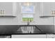 Modern kitchen sink with stainless steel faucet, granite countertop, white cabinets, and a view to the outside at 1300 Austin Chaney Rd, Wingate, NC 28174