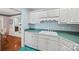 Bright kitchen with white cabinets and turquoise countertops, adjacent to a dining area with hardwood floors at 1911 Connemara Ct, Gastonia, NC 28054