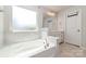 A bright bathroom features a soaking tub with marble surround, double sink vanity, and a large window at 19113 Hawk Haven Ln, Charlotte, NC 28278