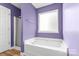 Bathroom featuring lavender walls, a tub under a window, and a shower at 2018 Arlington Ave, Statesville, NC 28677