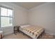 Neutral bedroom with a large window, light-colored carpet, and a bed with a tan plaid blanket at 4246 Millstream Rd, Denver, NC 28037