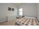 Neutral bedroom with a large window, light-colored carpet, and a bed with a tan plaid blanket at 4246 Millstream Rd, Denver, NC 28037