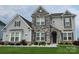 Charming two-story home featuring a stone facade, gray siding, manicured lawn, and professional landscaping at 7133 Sumters Camp Trl, Fort Mill, SC 29707