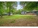 Expansive backyard featuring a shed and a view of the house, set against a backdrop of lush greenery at 8850 Hills Dell Dr, Concord, NC 28027