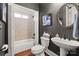 Bathroom featuring a pedestal sink, toilet, and tiled shower/tub combo. The dark walls provide contrast to the white features at 9433 Wallace Pond Dr, Huntersville, NC 28078