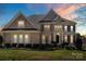 Charming two-story brick home with a lush green lawn and manicured landscaping at sunset at 9433 Wallace Pond Dr, Huntersville, NC 28078