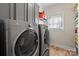 Convenient laundry room featuring modern washer and dryer with tile floor and storage shelves near window at 9433 Wallace Pond Dr, Huntersville, NC 28078