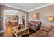 Inviting living room with hardwood floors, a cozy leather sofa, and an open archway to the dining area at 9433 Wallace Pond Dr, Huntersville, NC 28078
