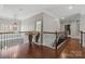 An upstairs hallway featuring hardwood floors, a decorative mirror, and views of the staircase and landing at 9433 Wallace Pond Dr, Huntersville, NC 28078