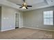 Neutral primary bedroom boasts a ceiling fan, plush carpet, and large windows for natural light at 12044 Brownestone View Dr, Charlotte, NC 28269