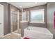 A bathroom features a soaking tub with a separate shower, neutral walls, and natural lighting at 15131 Oleander Dr, Charlotte, NC 28278