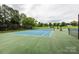 View of a tennis court with trees surrounding the perimeter on a partly cloudy day at 18861 Vineyard Point Ln, Cornelius, NC 28031