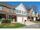 View of brick townhomes with garages, green shutters, and manicured lawns on a sunny day at 2021 Lennox Square Rd, Charlotte, NC 28210