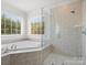 Elegant bathroom featuring tiled shower, soaking tub, and bright natural light from windows at 2907 Blackburn Dr, Waxhaw, NC 28173