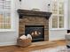 Close-up of a stone fireplace with a wooden mantle, flanked by windows with white shutters, and a basket of logs at 2907 Blackburn Dr, Waxhaw, NC 28173