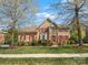 Charming two-story brick home featuring a manicured lawn, red shutters, mature trees, and a welcoming red front door at 2907 Blackburn Dr, Waxhaw, NC 28173