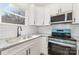 Well-lit kitchen featuring white cabinets, modern appliances, gray countertops, and stylish black hardware at 409 S Spargo St, Dallas, NC 28034