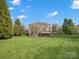 View of the back of the brick home with a spacious backyard and a deck looking out onto the well-maintained lawn at 5005 Autumn Blossom Ln, Waxhaw, NC 28173