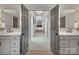 Bathroom featuring double sinks, white cabinets, and gray doors opening up to a carpeted hallway at 5005 Autumn Blossom Ln, Waxhaw, NC 28173