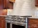 Close-up of a stainless steel range and oven, tile backsplash, and granite countertops at 5005 Autumn Blossom Ln, Waxhaw, NC 28173