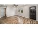 View of a light-filled living room with wood floors, a front door and an open doorway to another room at 5310 Myrica Ln, Charlotte, NC 28213