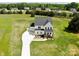 Stunning aerial view of white farmhouse, long driveway and expansive green yard, showcasing its serene setting at 623 Plowshare Way, Clover, SC 29710