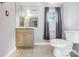 A simple, light filled bathroom featuring a traditional vanity, toilet, mirror and a window at 7201 Cedarfield Rd, Charlotte, NC 28227