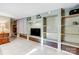 A spacious living room showcasing custom built-in shelving, cabinetry, and white tile floors at 7201 Cedarfield Rd, Charlotte, NC 28227