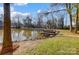 A lakefront property featuring a private dock surrounded by lush greenery and trees at 7201 Cedarfield Rd, Charlotte, NC 28227