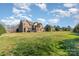 View of the home's backyard with lush green lawn and a brick house at 8137 Caliterra Dr, Charlotte, NC 28227