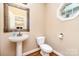 This powder room features a pedestal sink with an ornate mirror and a window for natural light at 8137 Caliterra Dr, Charlotte, NC 28227