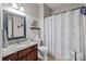 Bathroom featuring granite countertop, decorative mirror, and shower with patterned curtain at 8606 Chatsworth Ln, Waxhaw, NC 28173