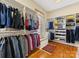 A spacious walk-in closet with custom shelving, hardwood floors, a bench, and ample storage for clothes and shoes at 8915 Heydon Hall Cir, Charlotte, NC 28210