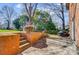 Patio extending into a backyard with a grill, wooden fence, and landscaping near a brick home at 1301 Old Farm Rd, Charlotte, NC 28226