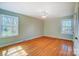 Bright bedroom with hardwood floors, two windows, and a ceiling fan at 1301 Old Farm Rd, Charlotte, NC 28226