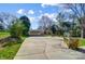Long concrete driveway leading to a carport, surrounded by greenery and a fenced yard at 1301 Old Farm Rd, Charlotte, NC 28226