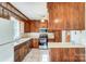 Traditional kitchen with wood cabinetry, modern stainless steel appliances, and a view of the staircase at 1301 Old Farm Rd, Charlotte, NC 28226