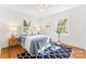 Bright bedroom featuring hardwood floors, two windows, ceiling fan, and stylish blue patterned rug at 1416 Woodland Dr, Charlotte, NC 28205