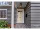 Close-up of a charming yellow front door with decorative glass and house number, set against a gray exterior at 1416 Woodland Dr, Charlotte, NC 28205