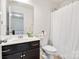 Bathroom featuring a dark vanity, white toilet, and shower curtain; clean and practical design at 14815 Superior St, Charlotte, NC 28273