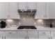 Close up on modern stovetop and range hood against a light backsplash at 15035 Batteliere Dr, Charlotte, NC 28278