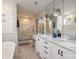 Bright bathroom featuring double sink vanity, large mirrors, soaking tub, and a glass enclosed shower at 1703 Luther St, Charlotte, NC 28204